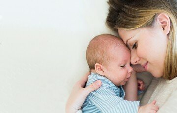 Mother with her newborn baby son lying on bed